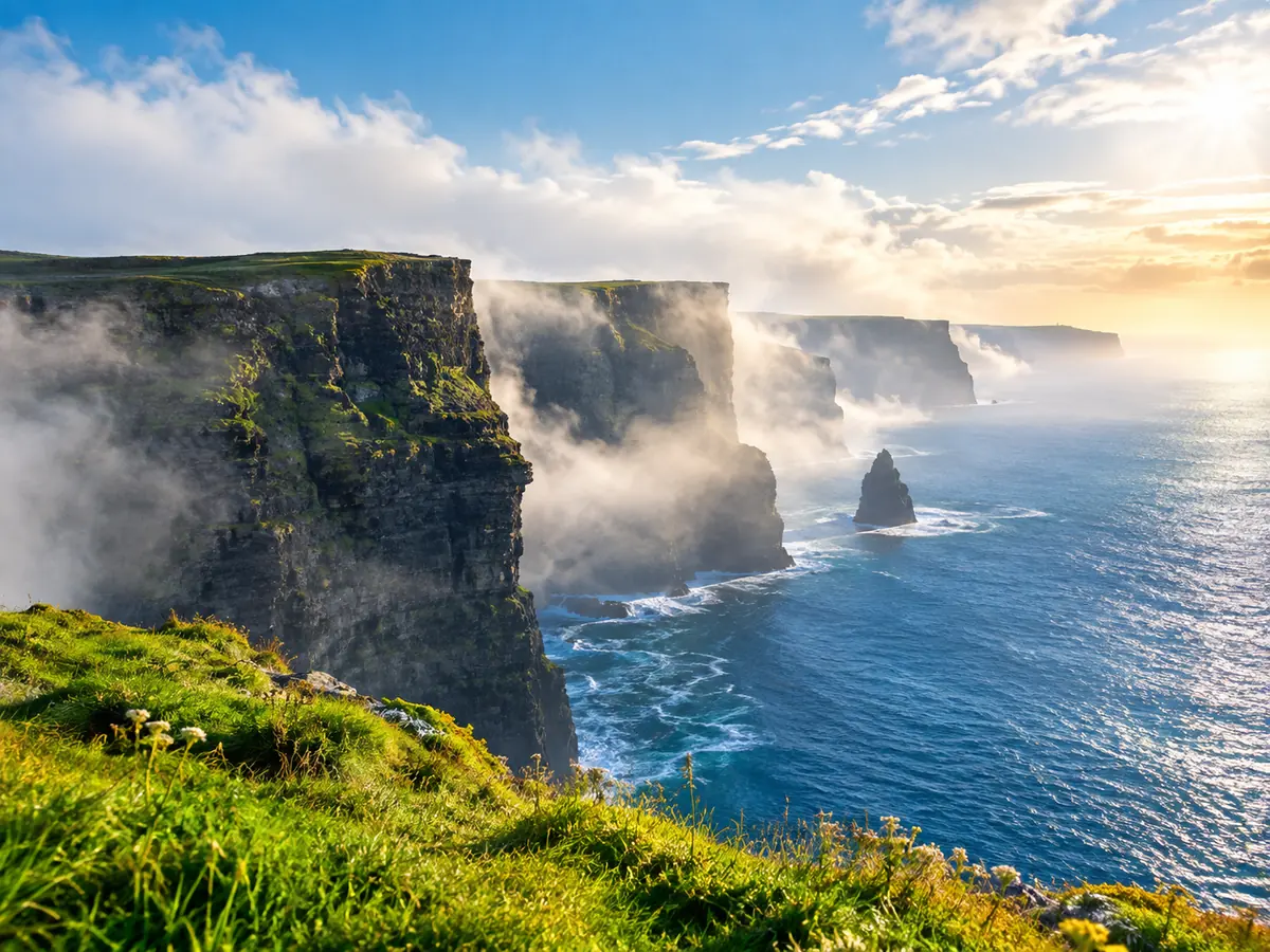 Seenebel lichtet sich über den Cliffs of Moher, die Sonne bricht durch